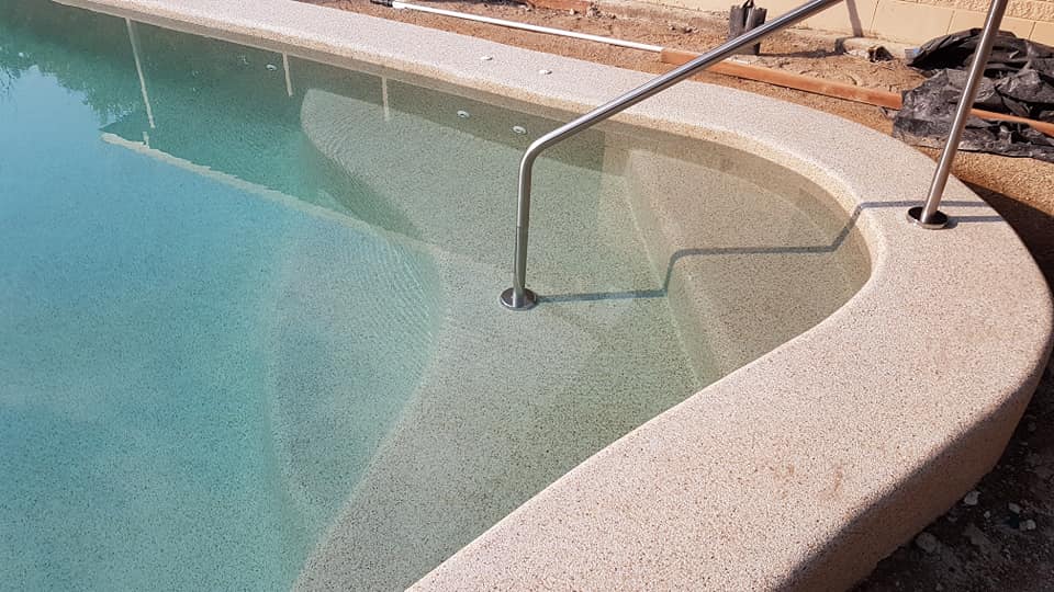 A Swimming Pool With Stairs Leading to It and a Metal Railing — NQ Tropical Pools & Renovations in Cranbrook, QLD