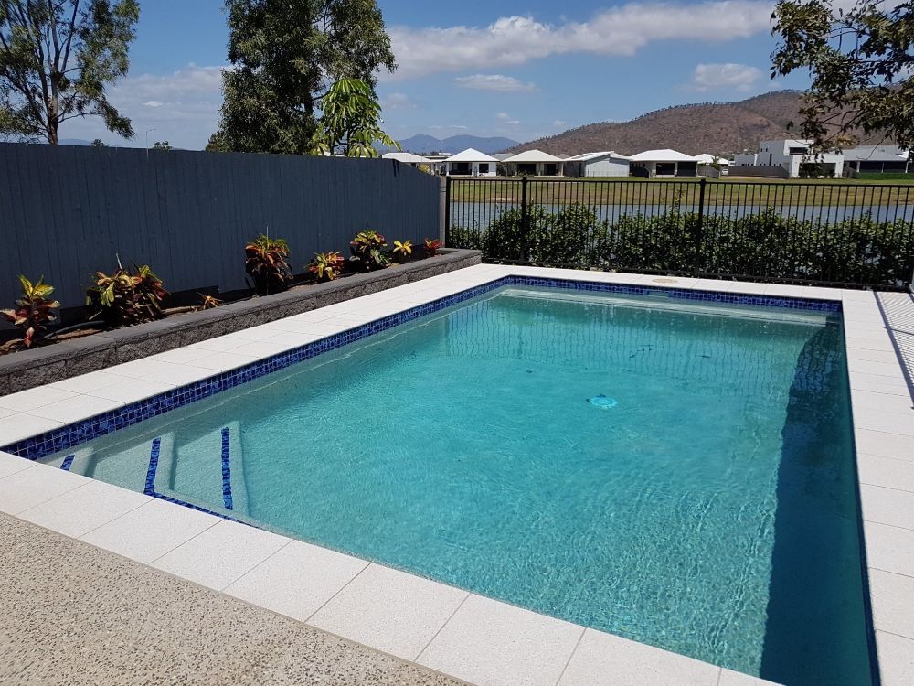 A Large Swimming Pool With a Fence Around It — NQ Tropical Pools & Renovations in Cranbrook, QLD