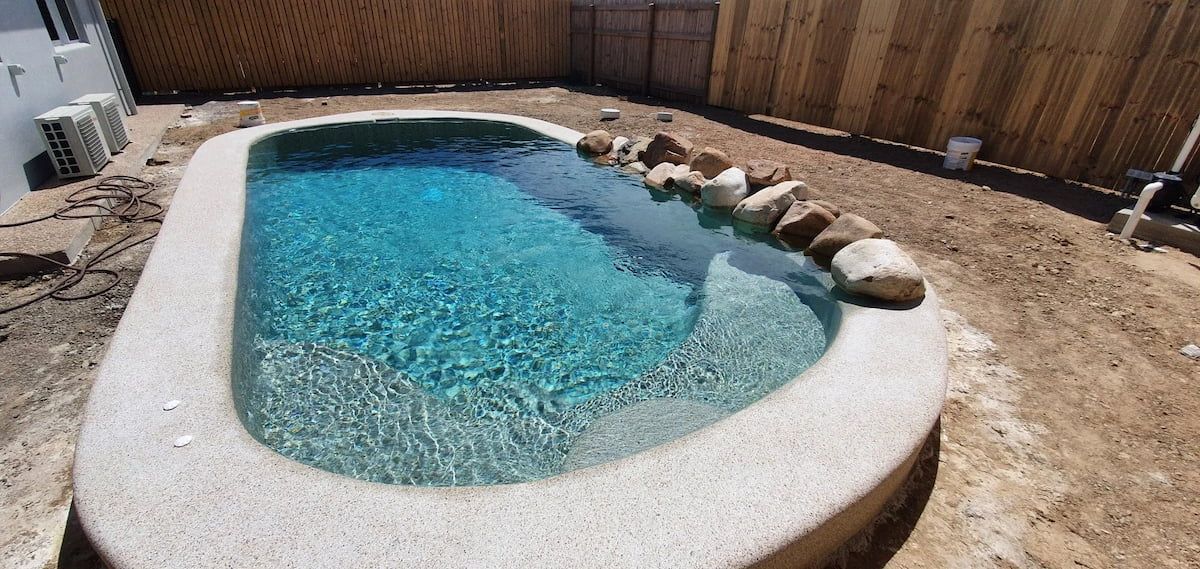 A Small Swimming Pool With a Wooden Fence in the Background — NQ Tropical Pools & Renovations in Cranbrook, QLD