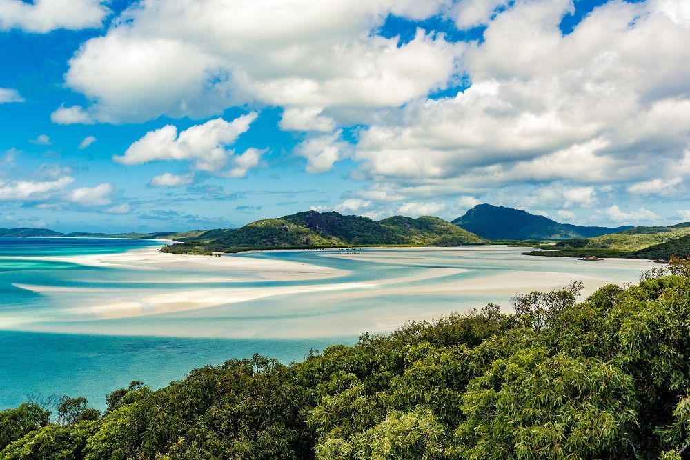 A Large Body of Water Surrounded by Trees and Mountains — NQ Tropical Pools & Renovations in Airlie Beach, QLD