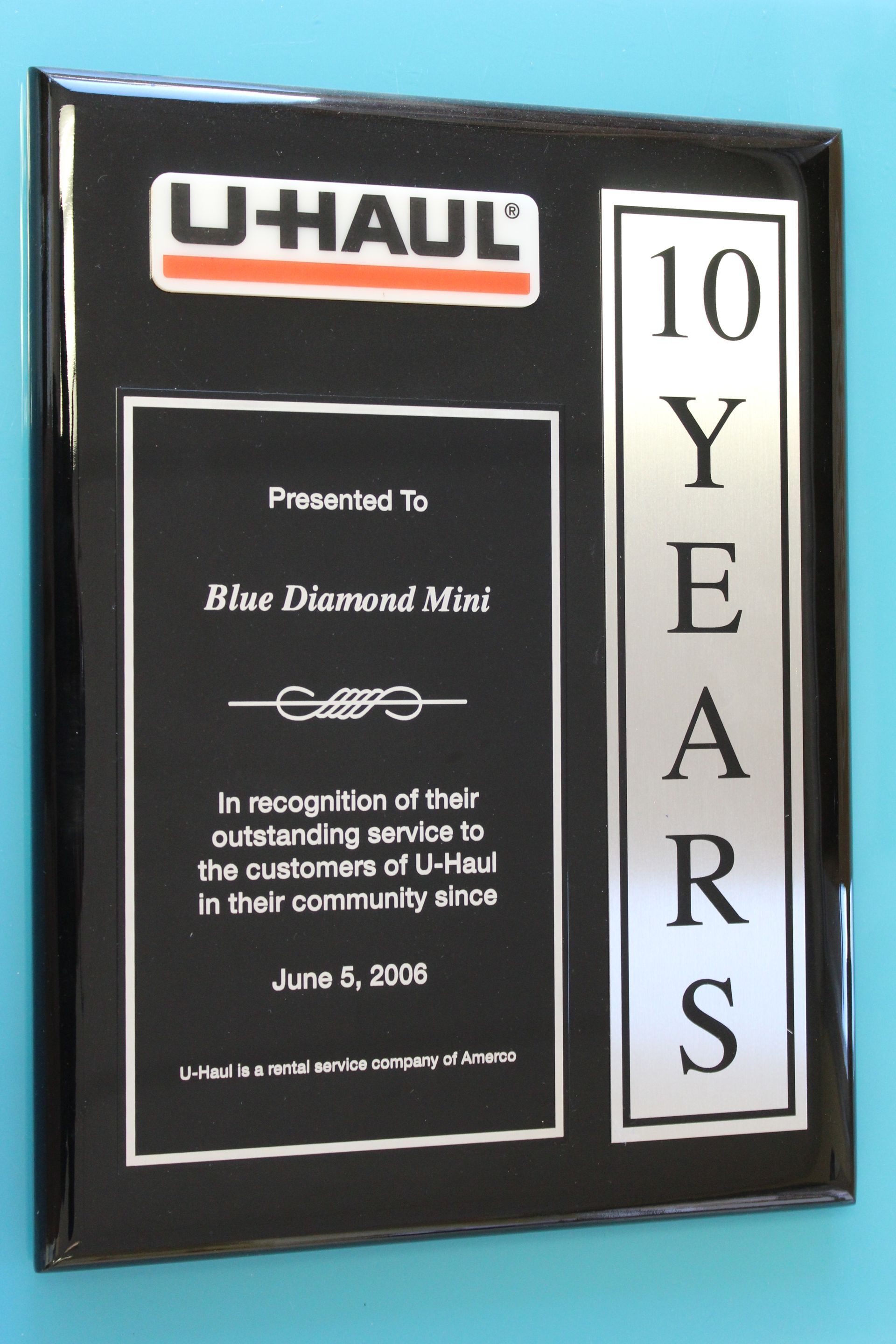 Black plaque with a U-Haul logo, text recognizing 10 years of service to customers in their community.