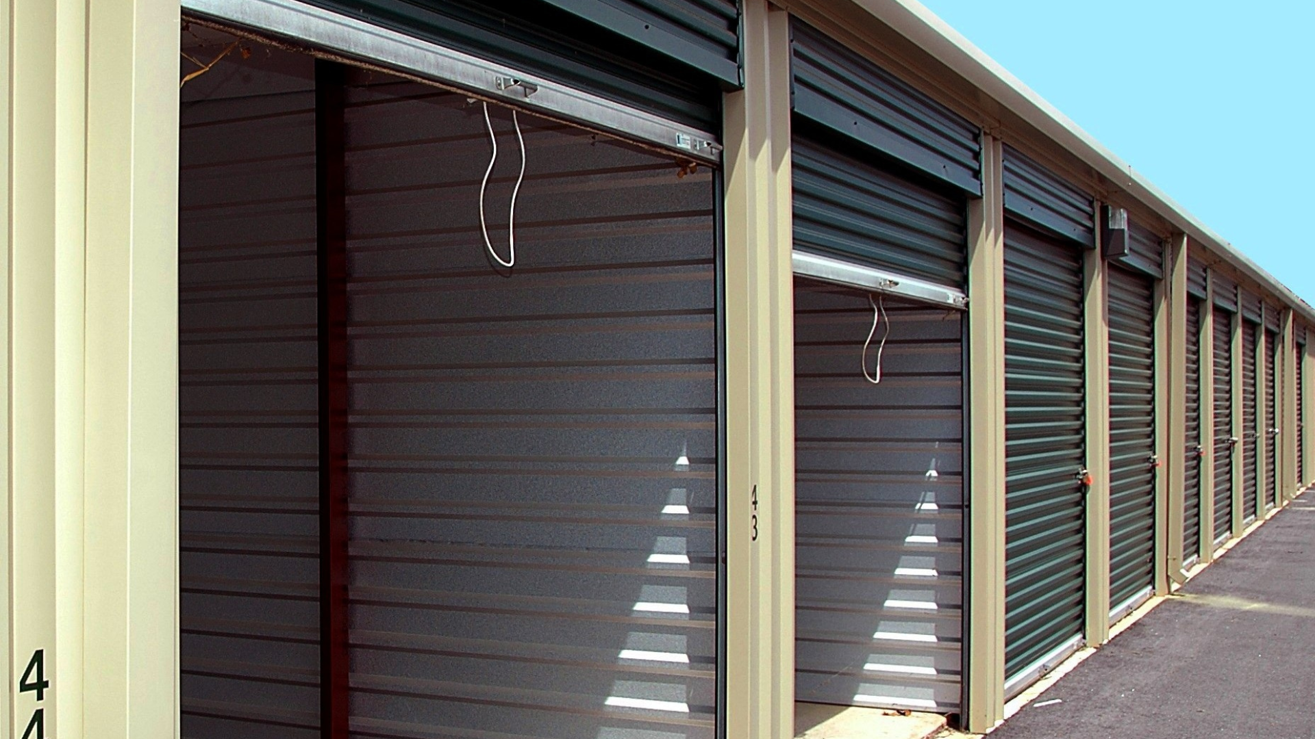 Row of beige storage units with partially open green doors.