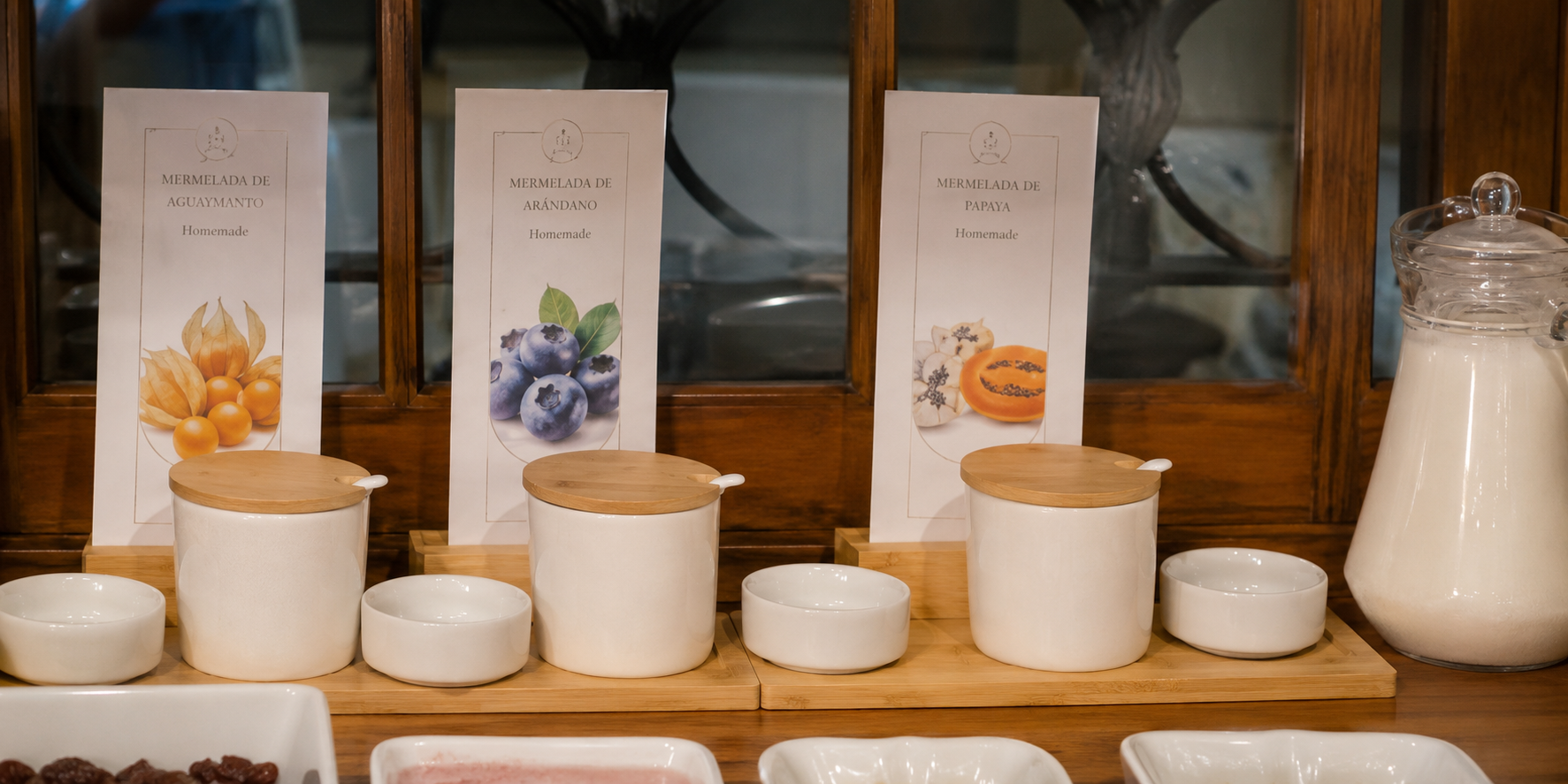 Latas y cuencos de té blanco dispuestos sobre un mostrador de madera con envases al fondo.