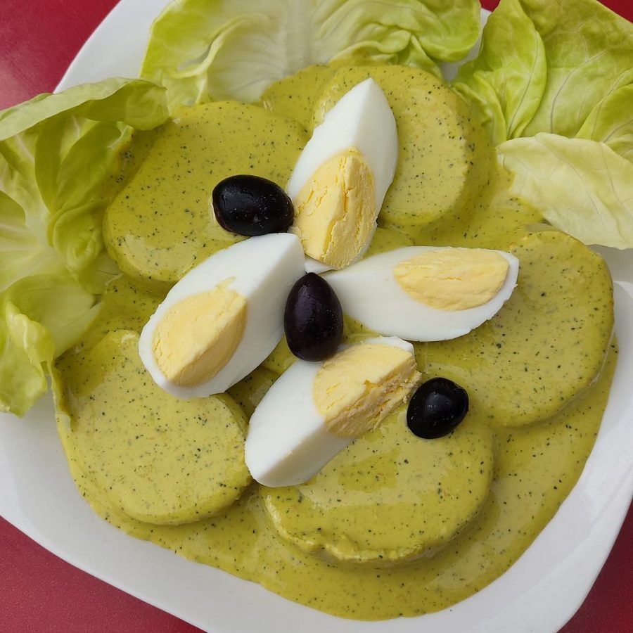 Ensalada con lechuga, pepino en rodajas, gajos de huevo duro y aceitunas negras en un plato blanco.