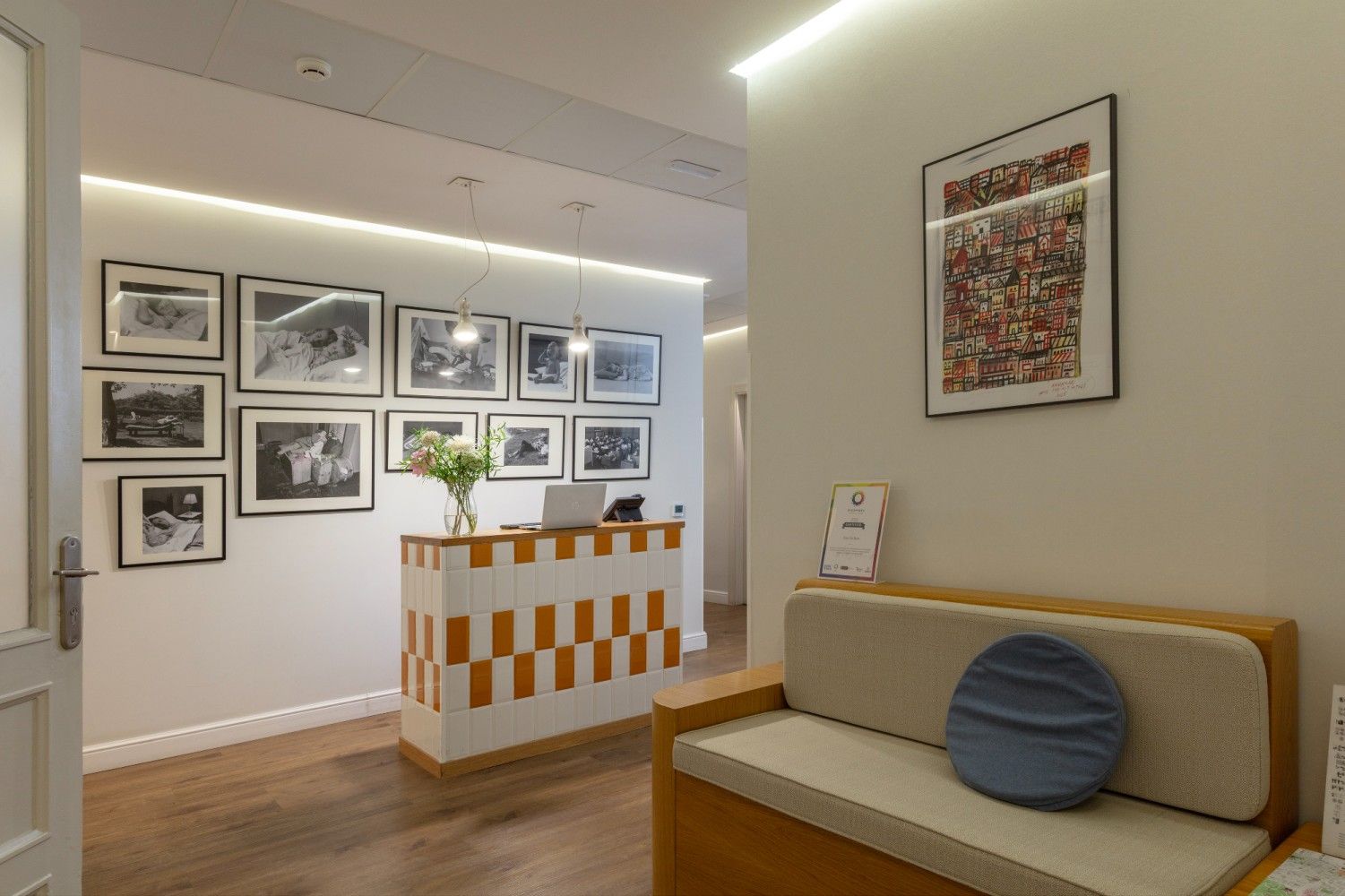 Un mostrador de recepción en el vestíbulo de un hotel con azulejos blancos y naranjas, un sofá con una almohada azul .