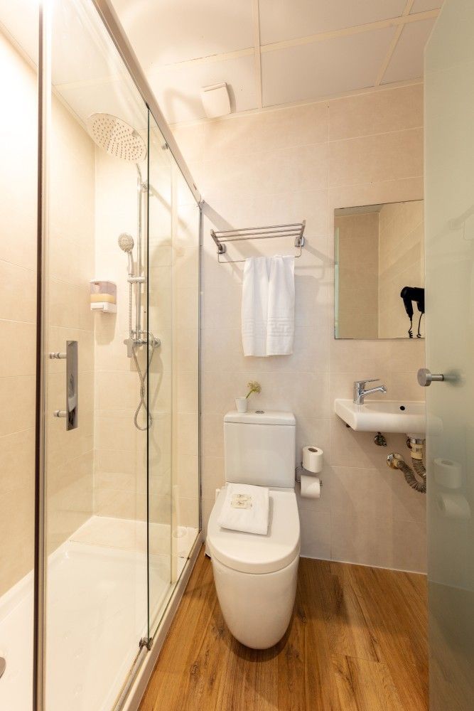 Un baño pequeño y limpio con una ducha con mampara de cristal, un inodoro con una toalla encima.