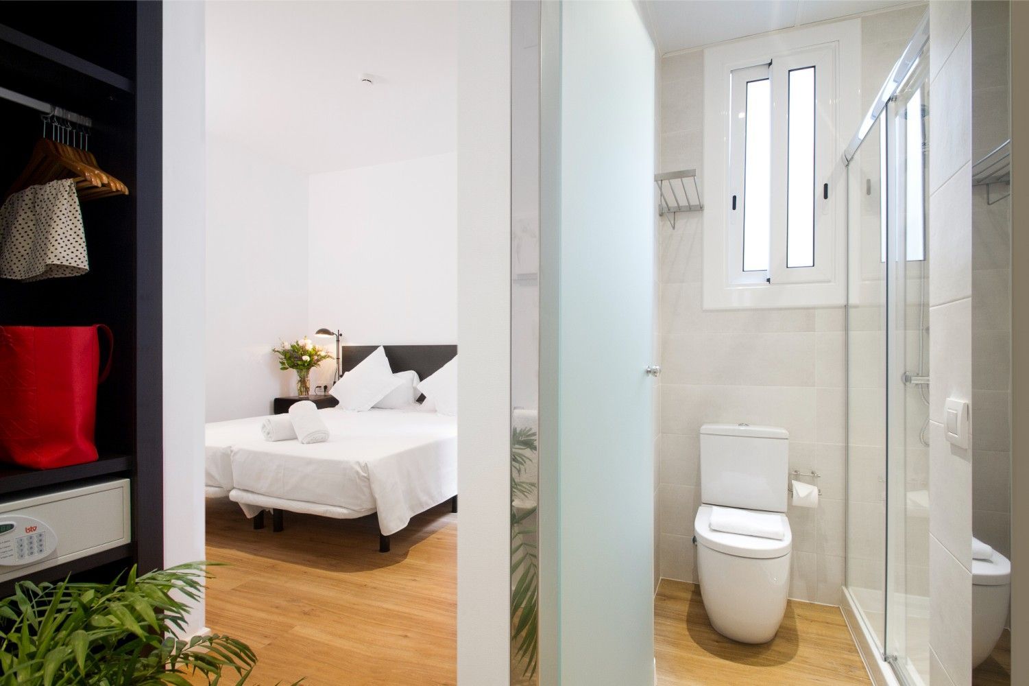 Una habitación de hotel con un dormitorio con una cama a la izquierda y un baño adyacente con inodoro y ducha a la derecha.