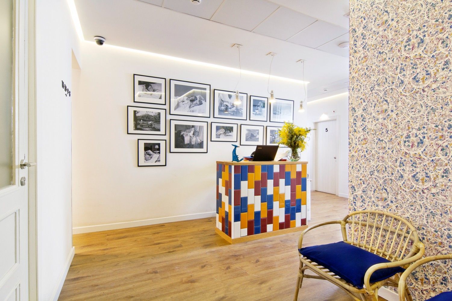 Área de recepción con un escritorio de azulejos de colores, arte de pared enmarcado, pisos de madera .