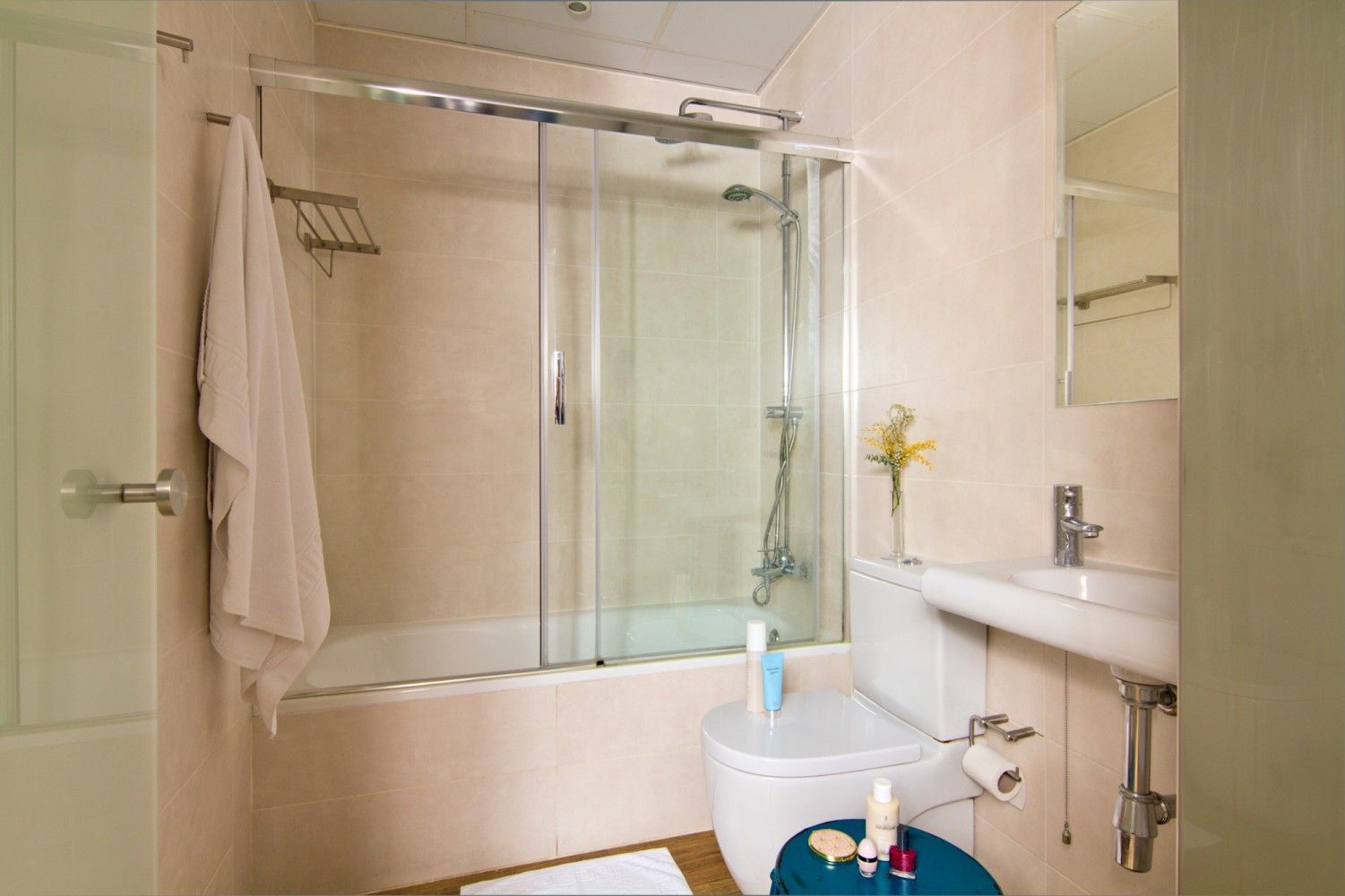 Un baño pequeño y moderno que cuenta con una ducha con puertas corredizas de vidrio, un inodoro blanco y un lavabo.