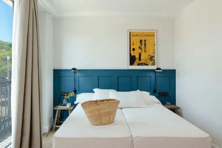 Un dormitorio minimalista con una cama contra una pared con paneles de color verde azulado, una canasta tejida.