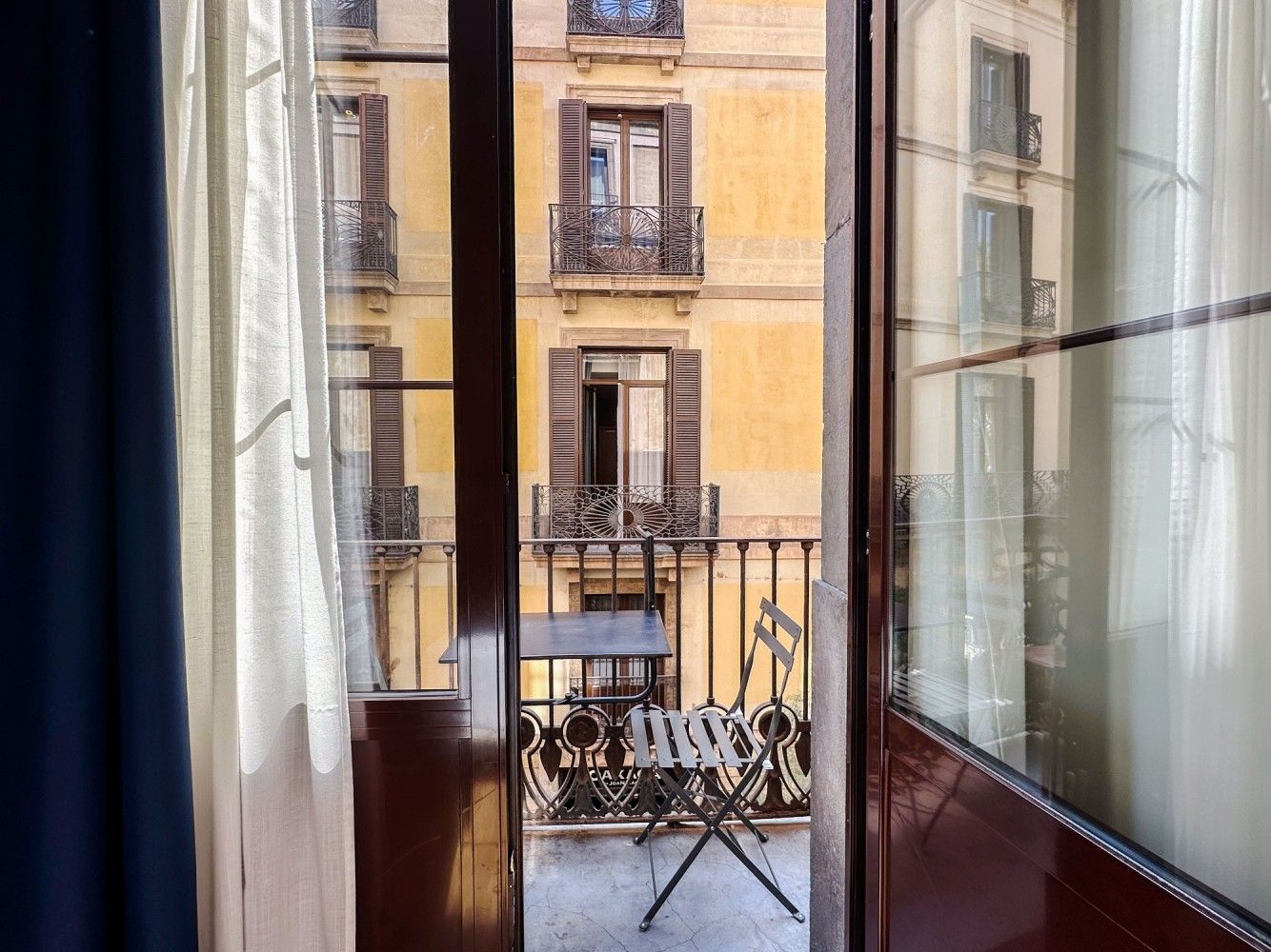 Una vista desde el interior de una habitación mirando a través de una puerta de balcón a un pequeño patio.