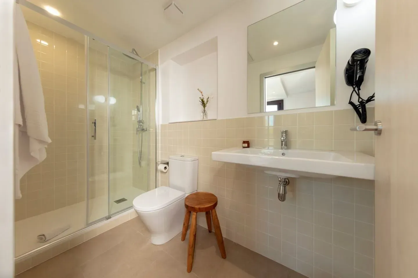 Un baño moderno y luminoso que cuenta con una ducha con puertas de vidrio, un inodoro blanco.