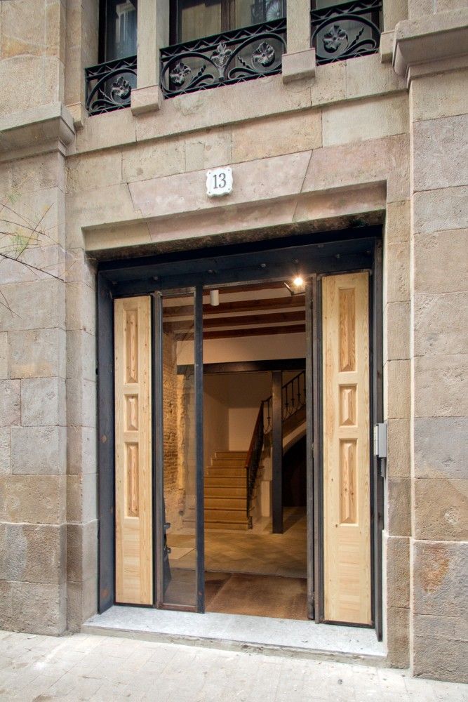 Una entrada a un edificio con paredes de piedra, el número 13 encima de la puerta y una puerta abierta.