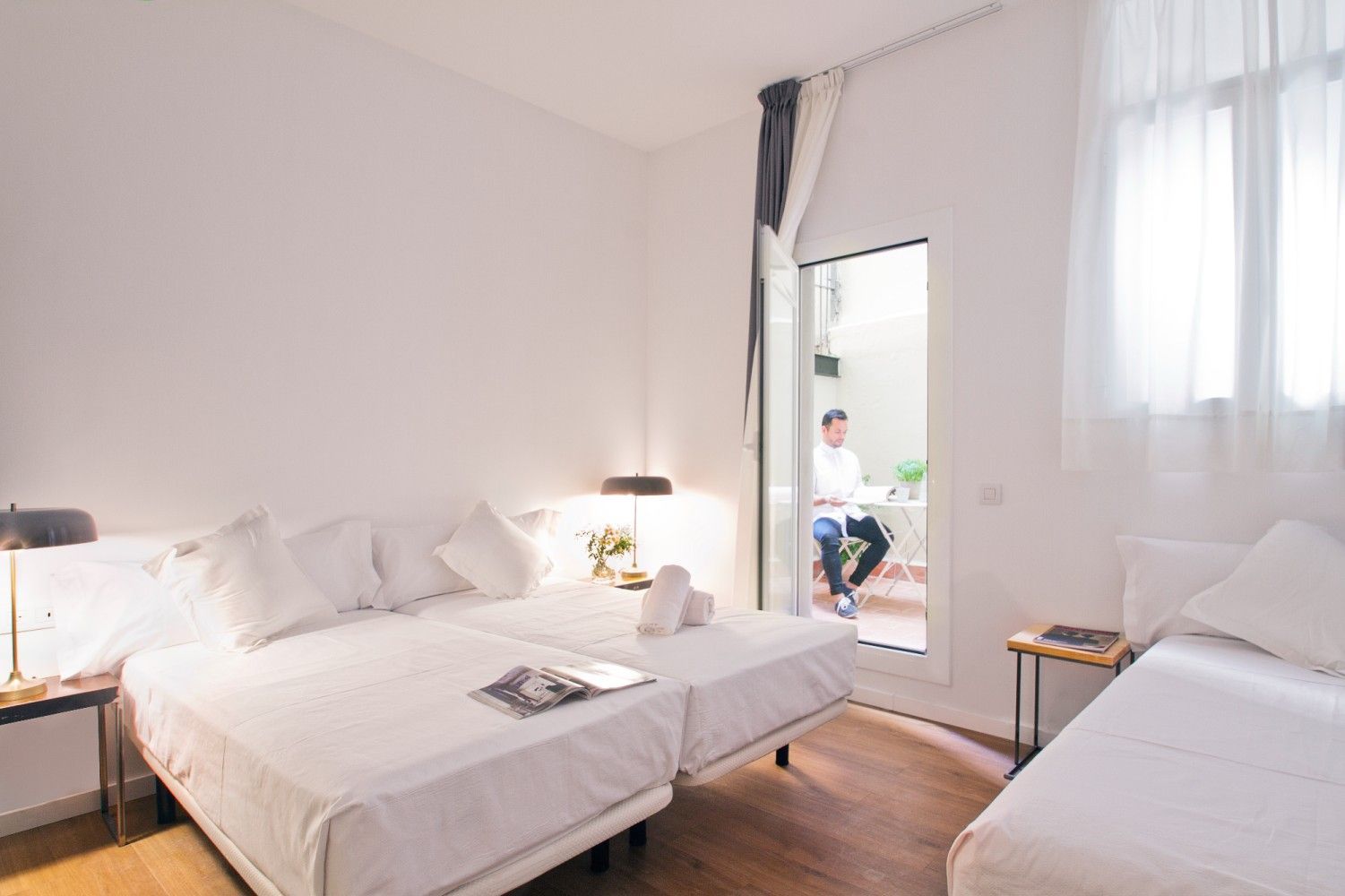 Un dormitorio luminoso con dos camas individuales, una tercera cama a un lado .