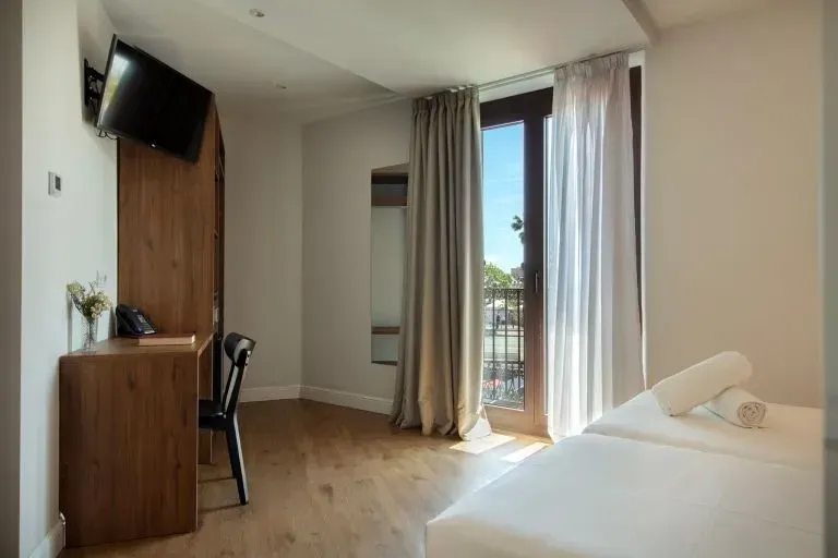 Una moderna habitación de hotel con dos camas blancas, un escritorio de madera con silla, un televisor.