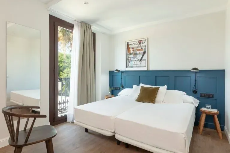 Una habitación de hotel con dos camas individuales, una cabecera con paneles de madera azules, una silla de madera.