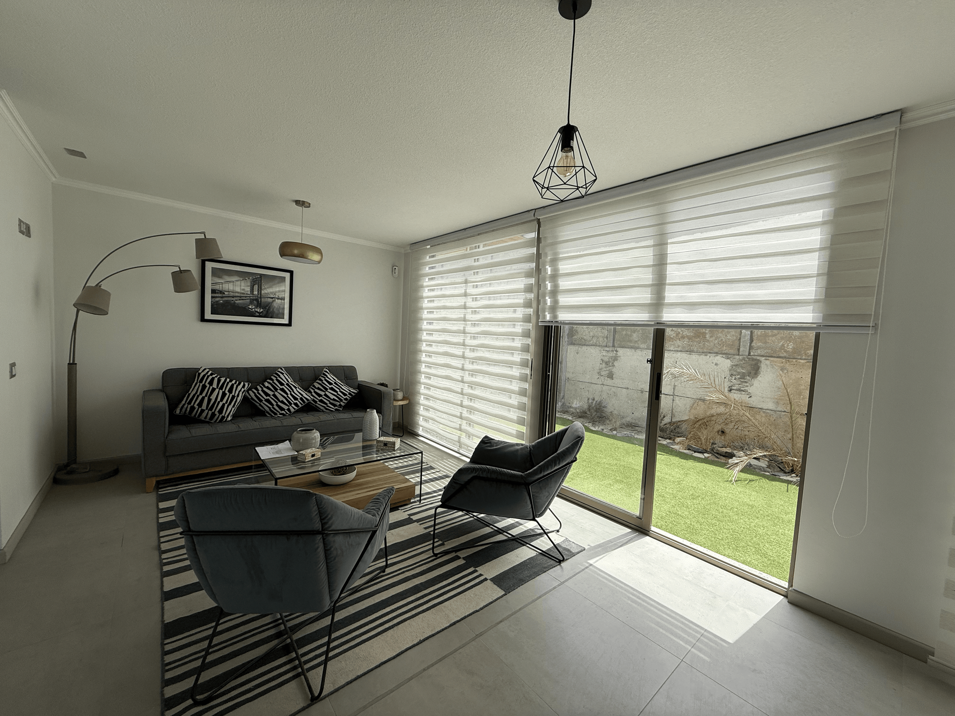 Una sala de estar con sofá, silla, mesa de café y puertas corredizas de vidrio.