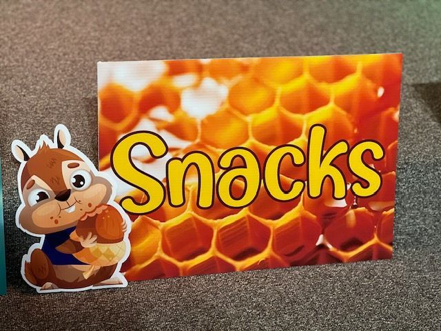 A chipmunk is standing next to a sign that says snacks