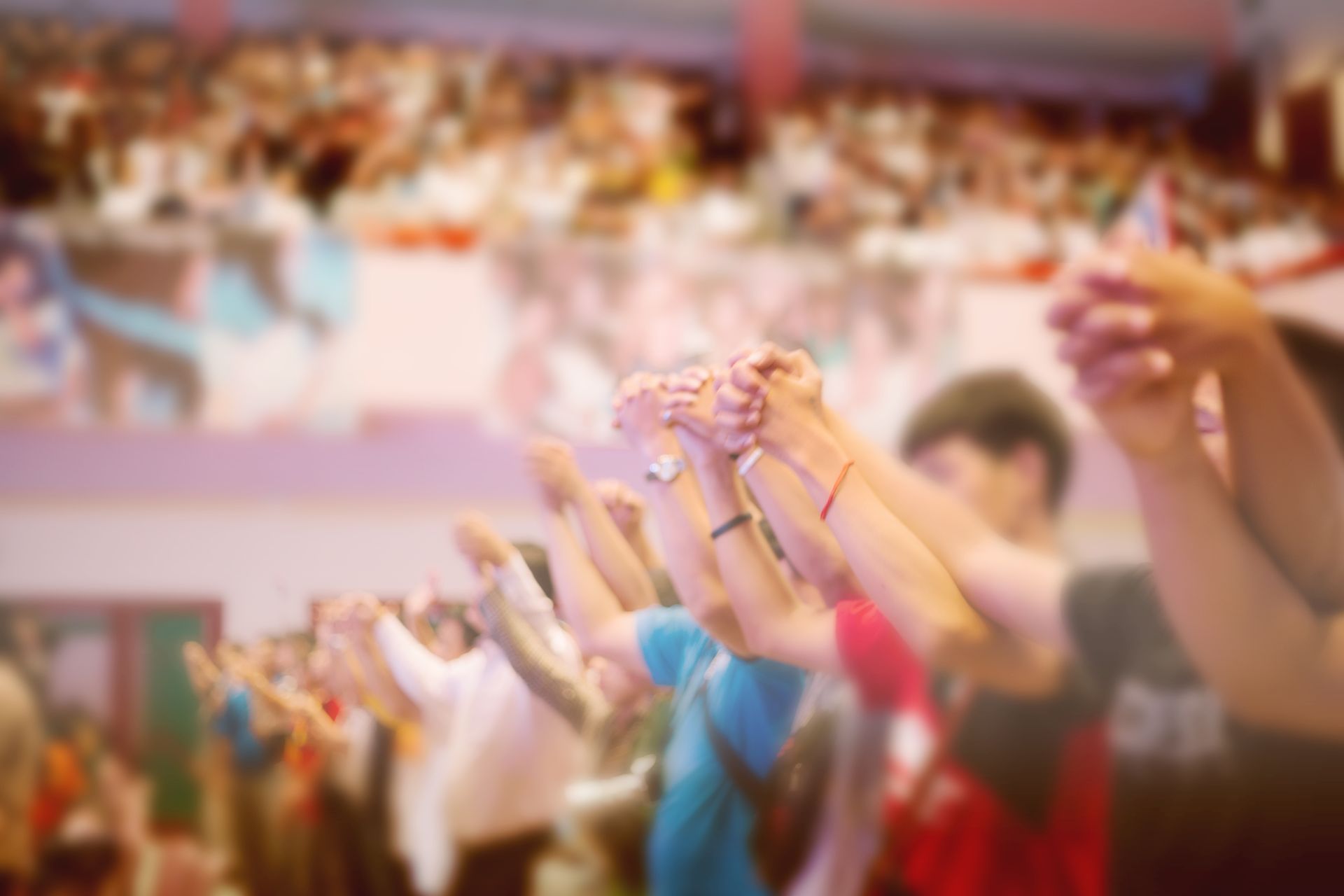A crowd of people are holding their hands up in the air.