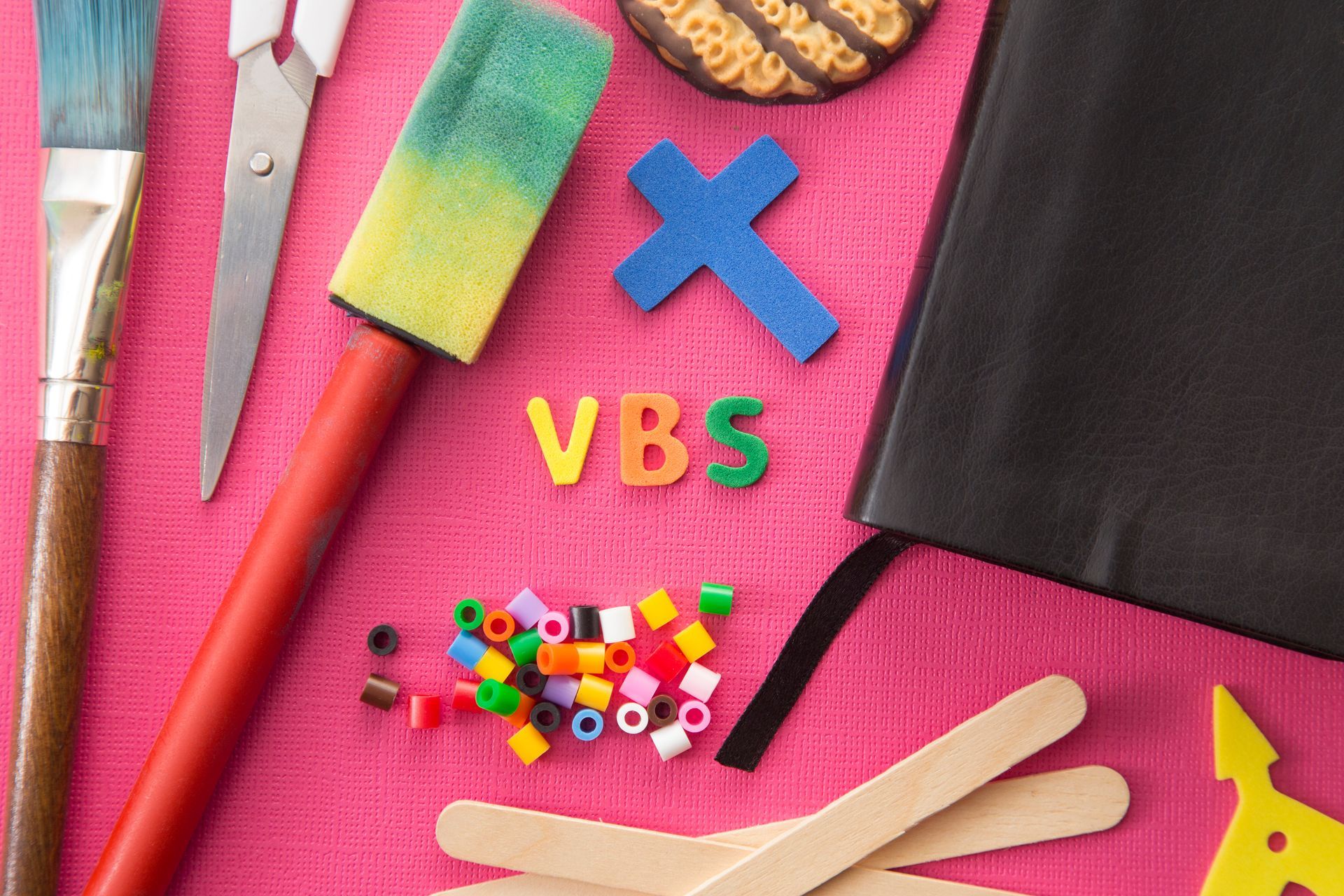 A bunch of craft supplies on a pink surface with the word vbs on it