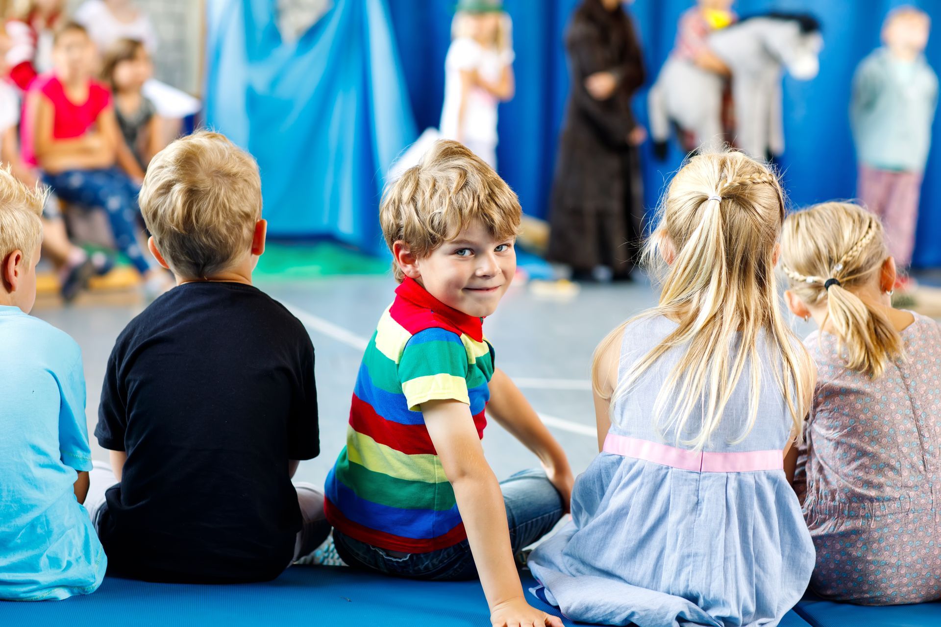 A group of children are sitting on the floor watching a play.