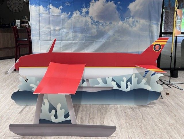 A red airplane is sitting on a wooden floor in front of a cloudy sky.