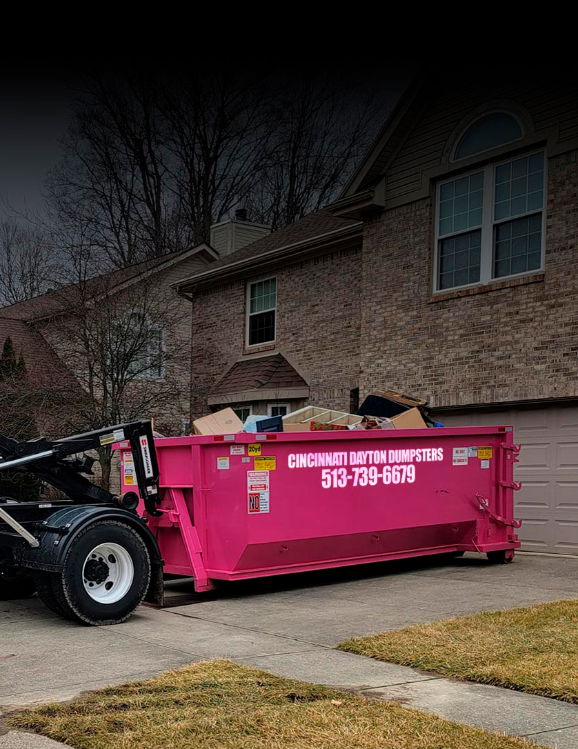 Pink dumpster on a trailer in front of a brick house