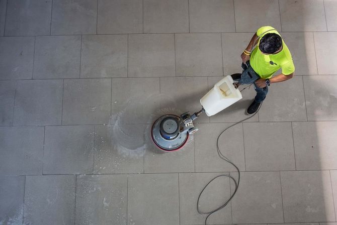 A man is cleaning a tiled floor with a machine.