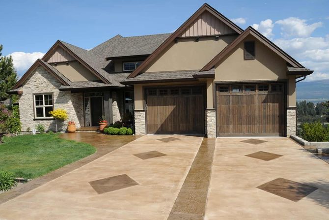 A large house with a wooden garage door and a concrete driveway