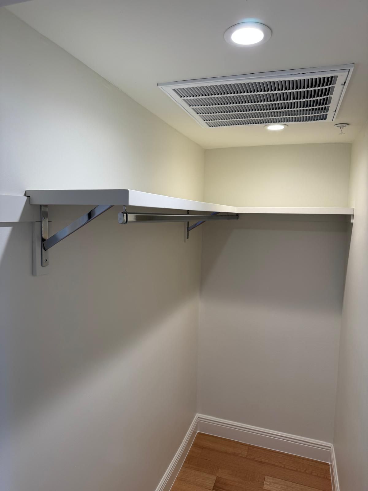 Empty closet with white walls, shelves, and a light.