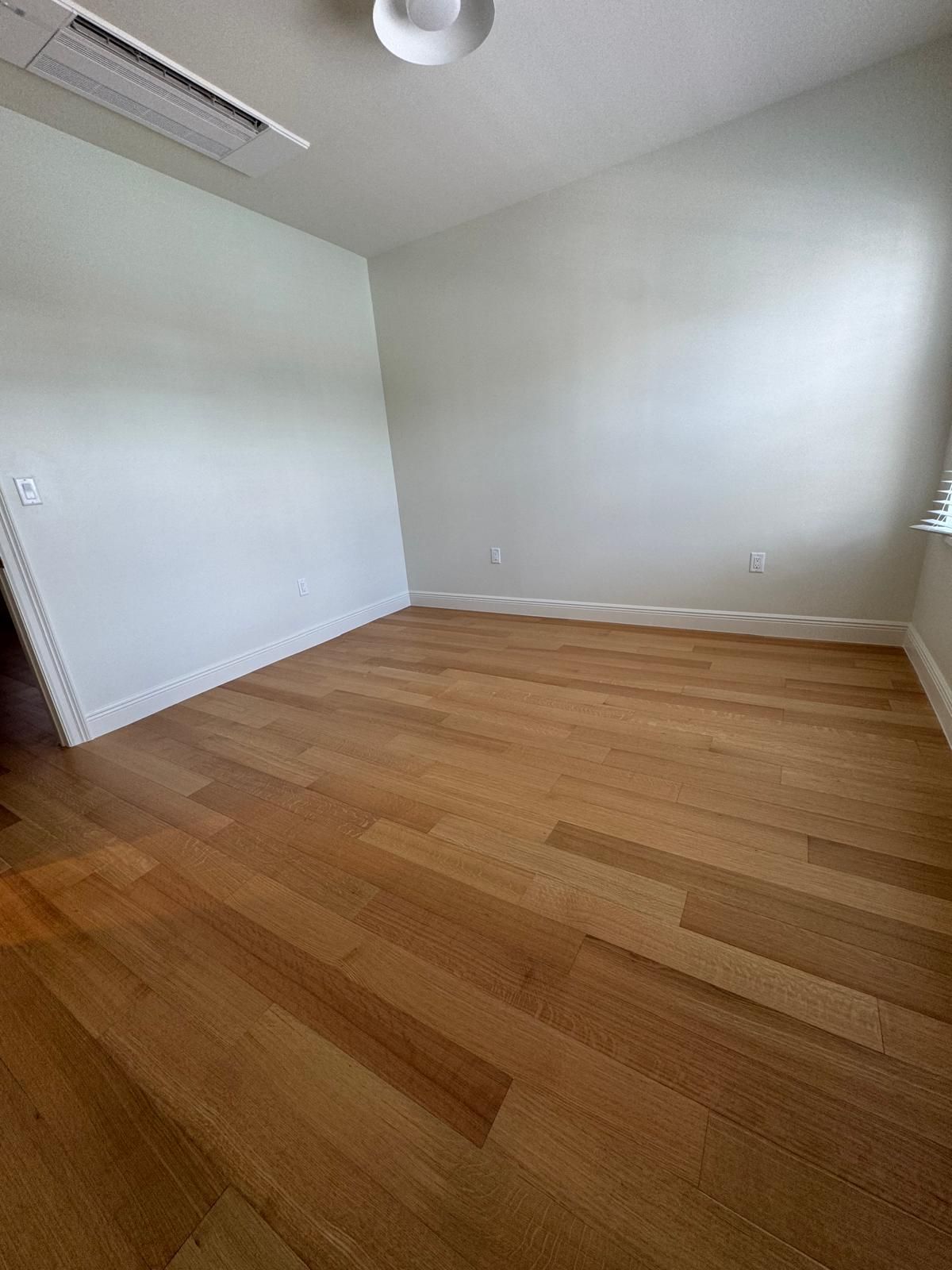 Empty room with hardwood floors and white walls.