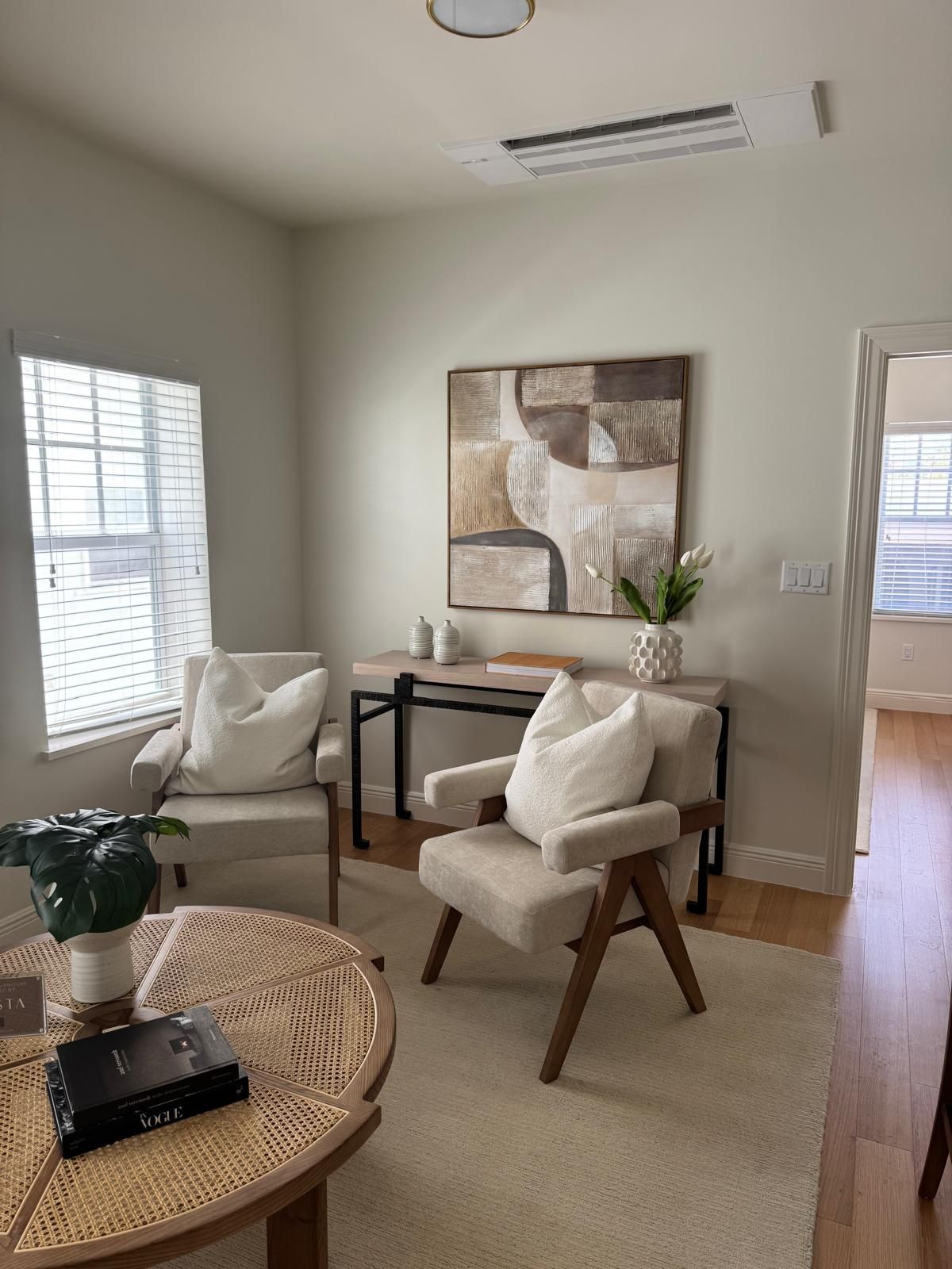 Living room with two armchairs, a coffee table, artwork, and a console table.