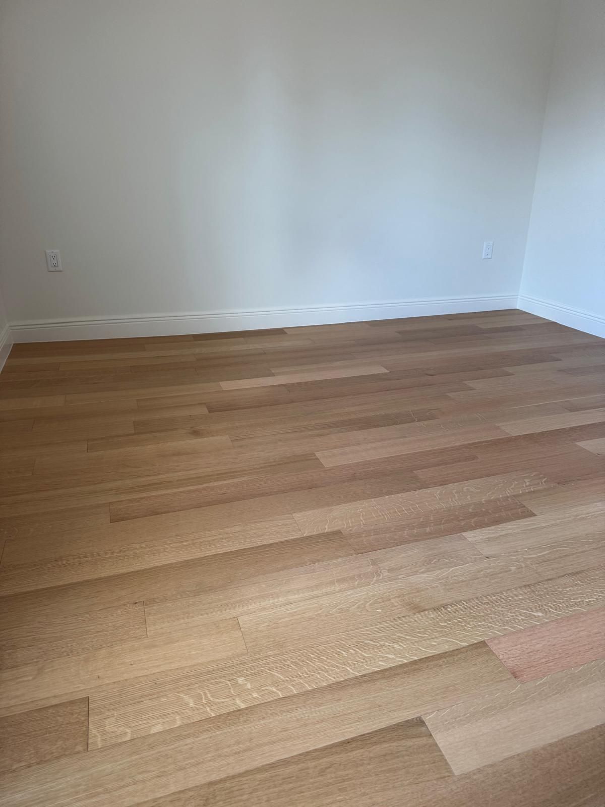 Light-colored wood floor in a room with white walls and trim.