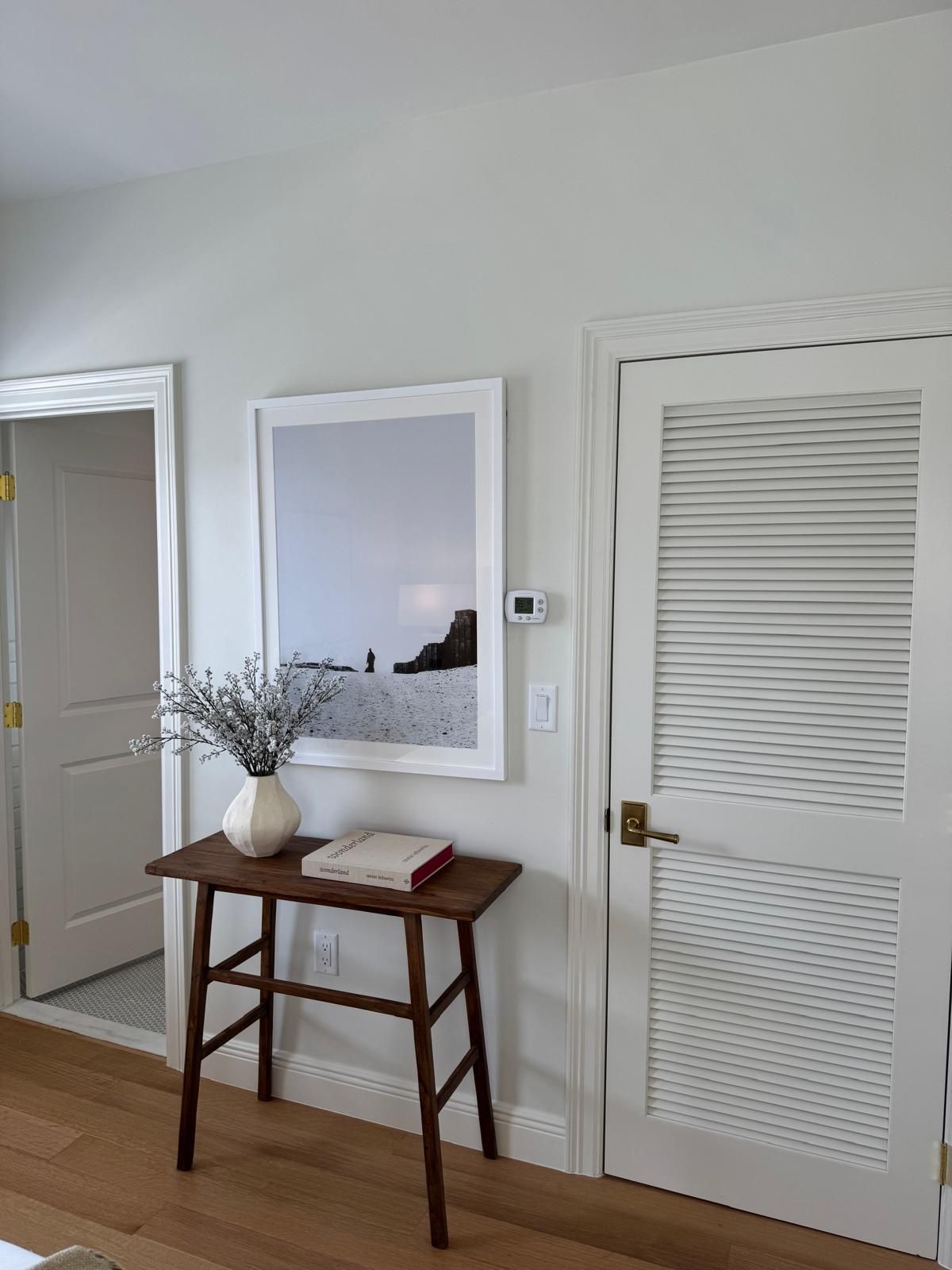 Wooden console table with decor, photo, and two white doors.