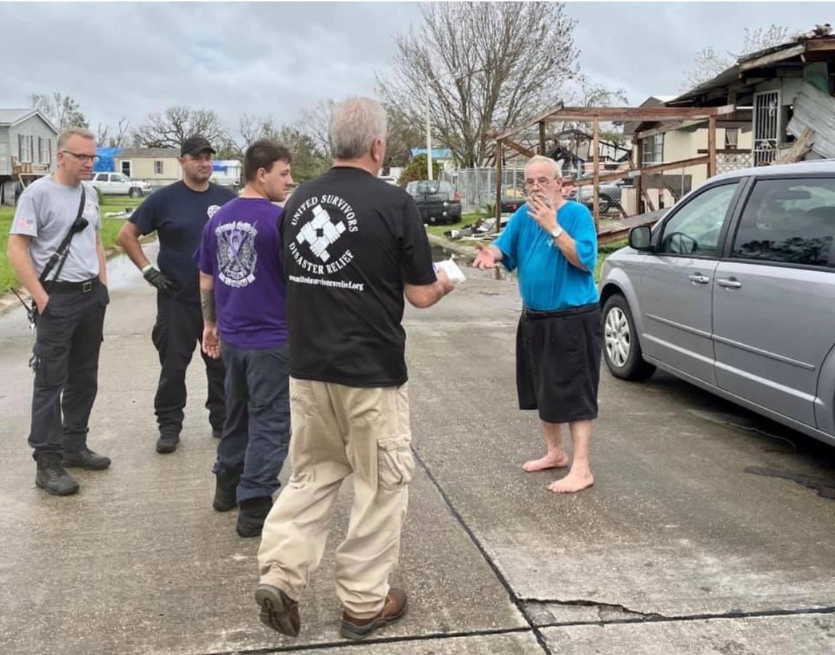 A group of men are standing in a parking lot talking to each other