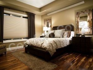 Bedroom with bed, window, nightstands, rug, and hardwood floor. Neutral colors, soft lighting.