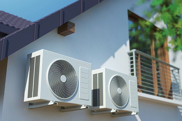 Two white air conditioning units mounted on the side of a white house. Two white air conditioning units mounted on the side of a white house.