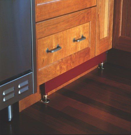 Kitchen cabinetry with drawer and red toe kick, sitting on short, decorative feet.