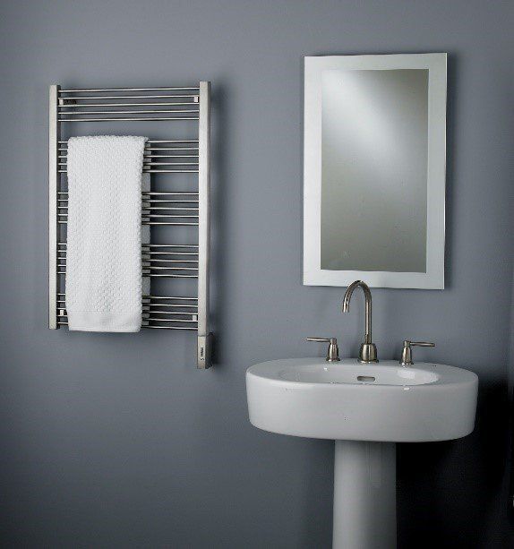 Towel warmer with towel, mirror, and sink against a gray wall.