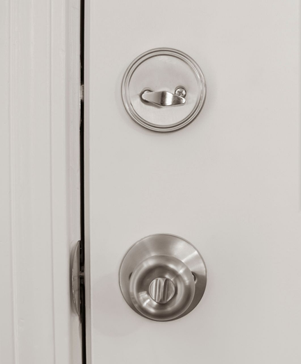 Door with a silver doorknob and lock, both on a white door.