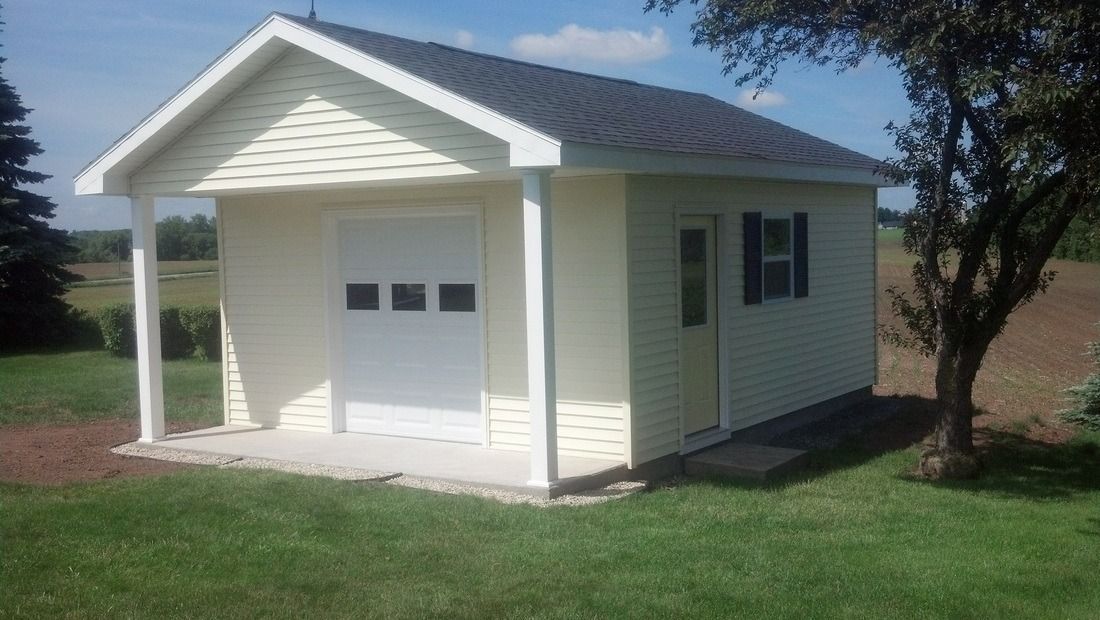 Yellow shed with white trim, a garage door, side door, and small window, on a grassy lawn.