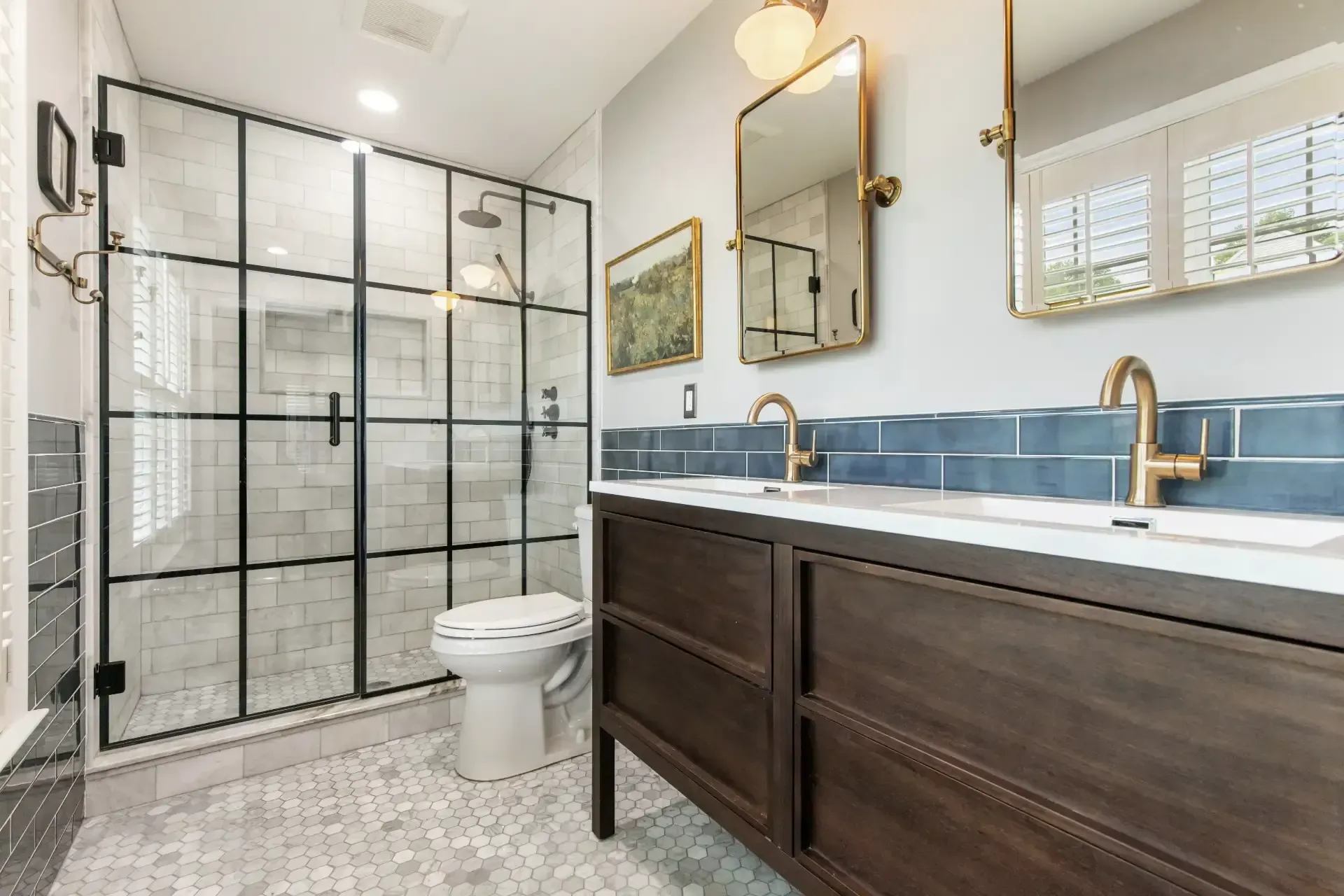 A bathroom with two sinks , a toilet , and a walk in shower.