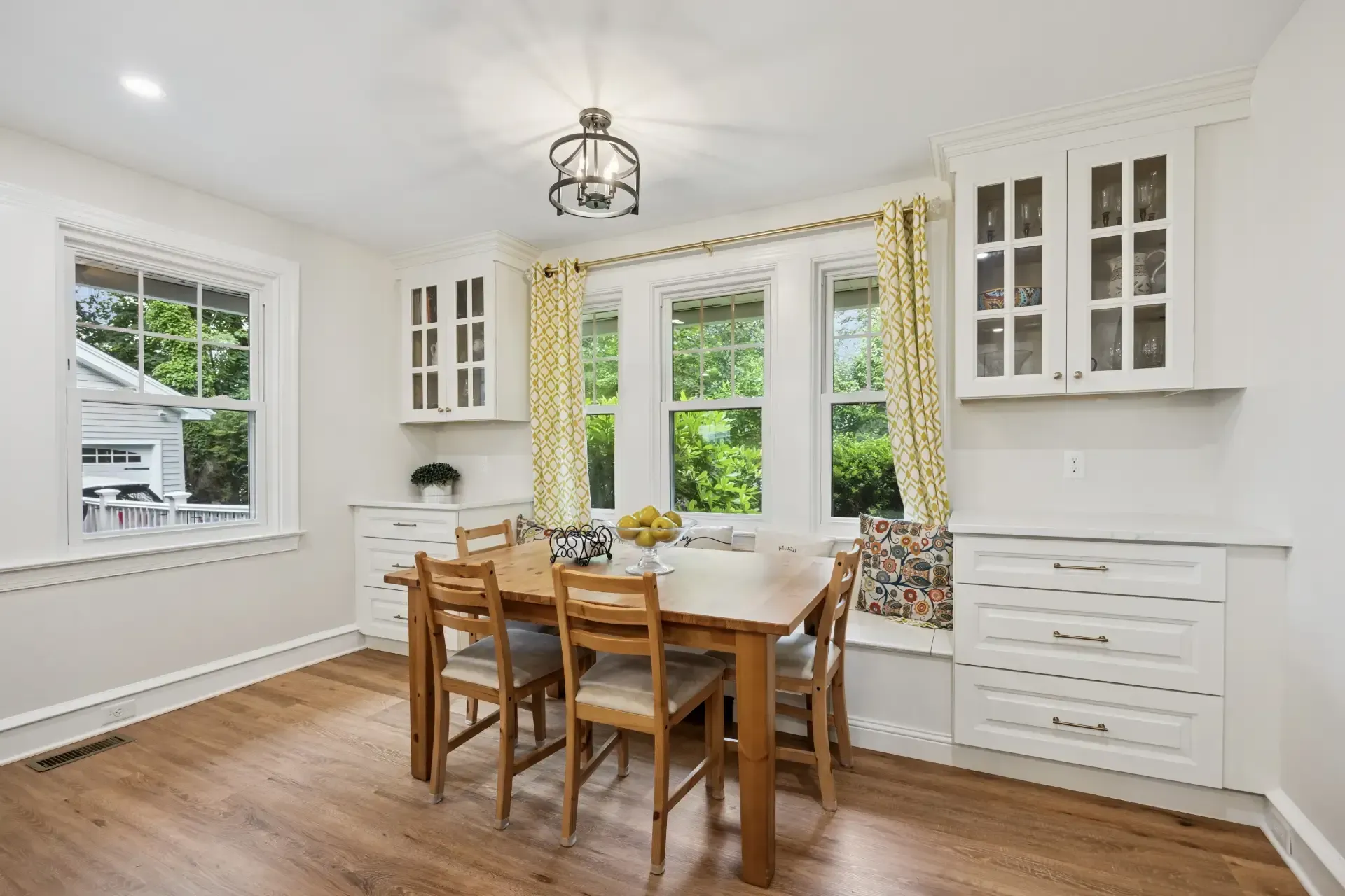 A dining room with a table and chairs and a window seat.