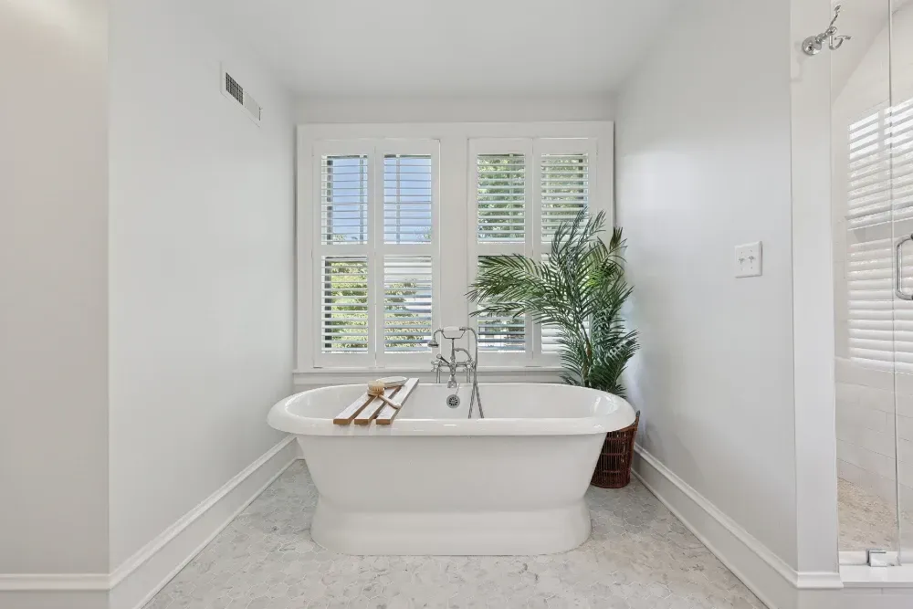 A bathroom with a tub , shower and window.