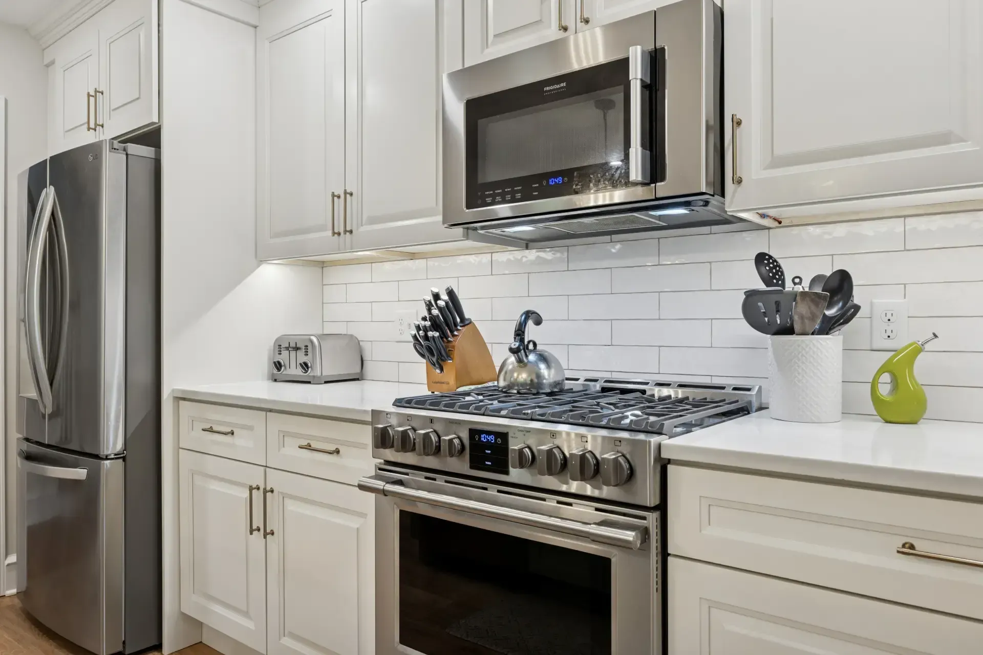 A kitchen with stainless steel appliances and white cabinets.
