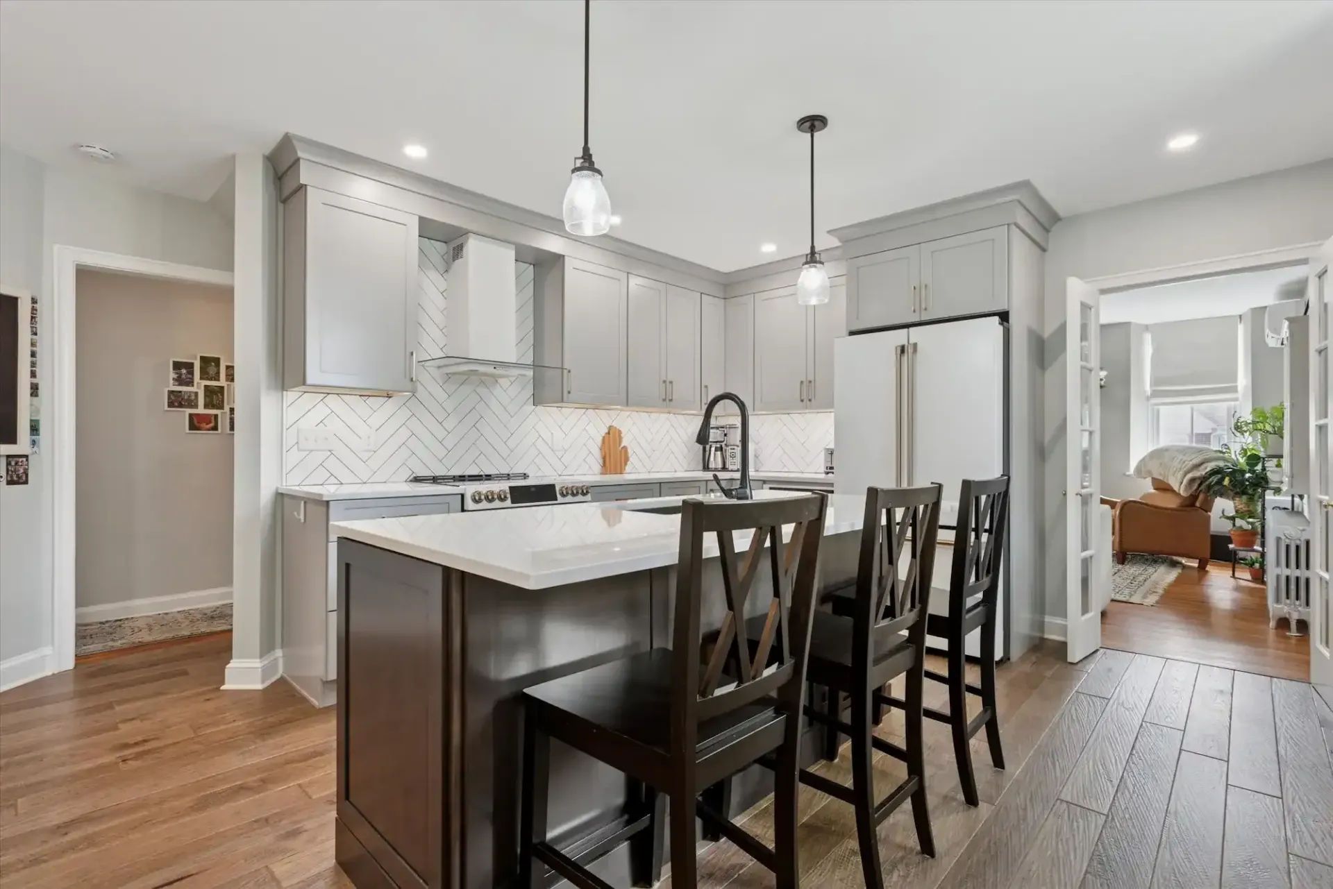 A kitchen with a large island and stools in it.