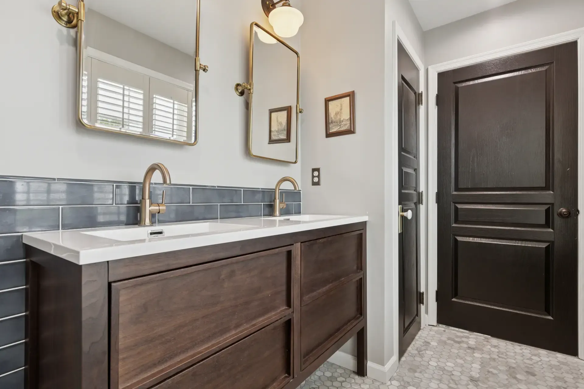 A bathroom with two sinks , a mirror and a door.