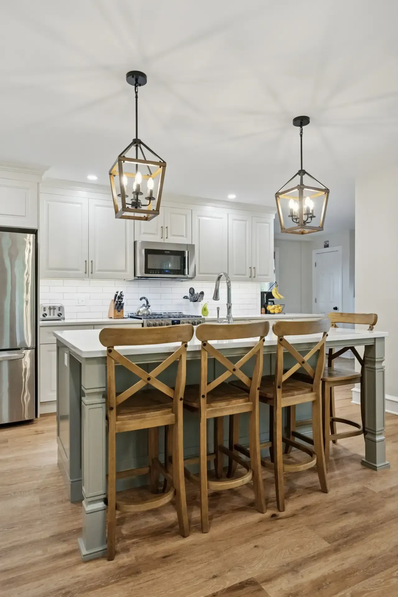 A kitchen with a large island , stools and pendant lights.