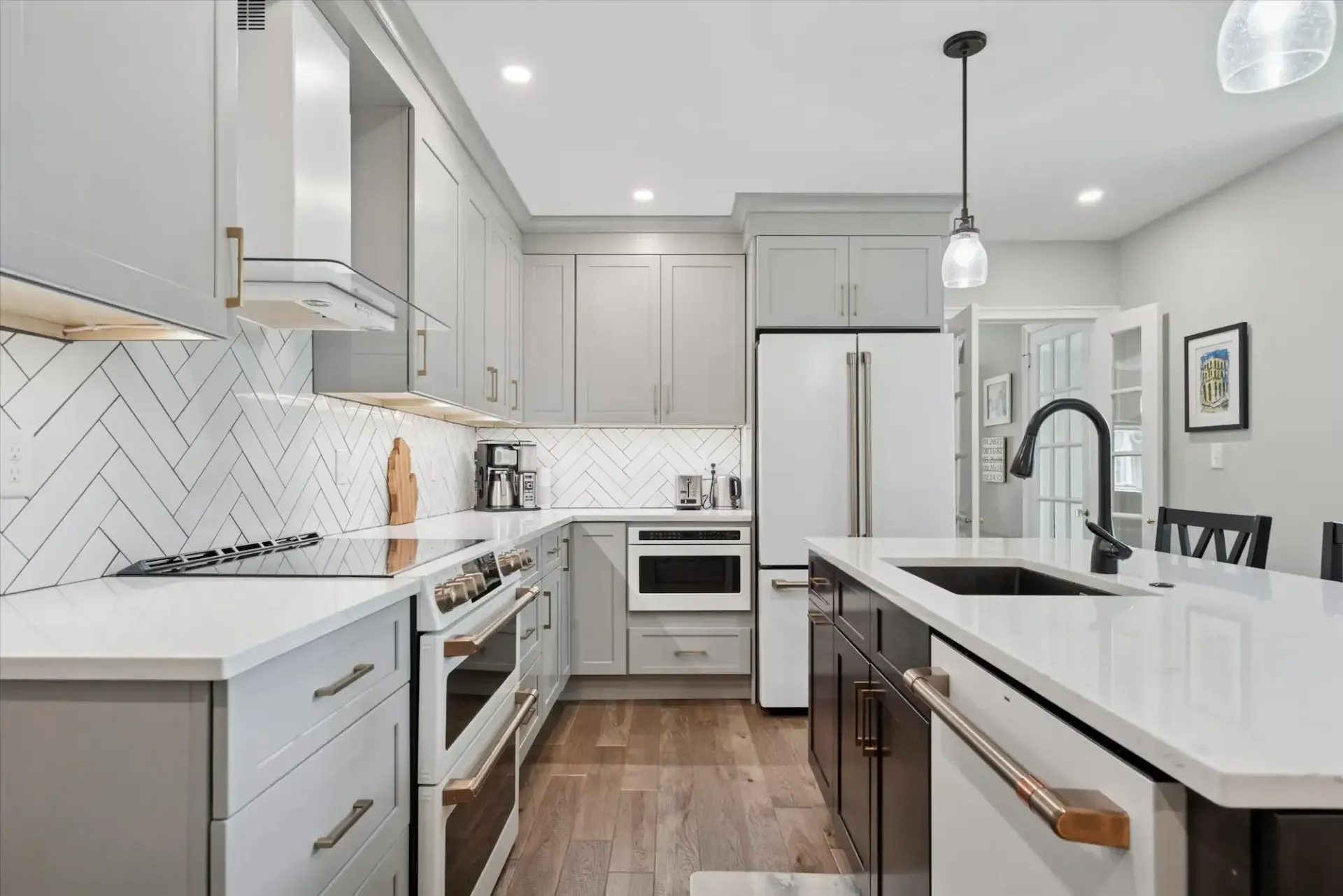 A kitchen with white cabinets , stainless steel appliances , a sink , and a refrigerator.