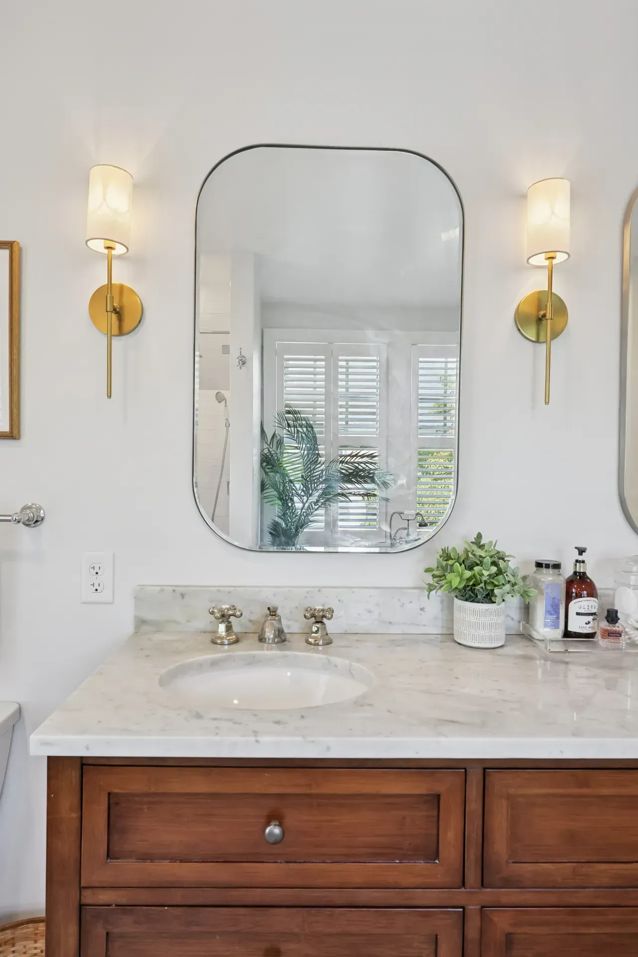 A bathroom with a sink , mirror and two lights.